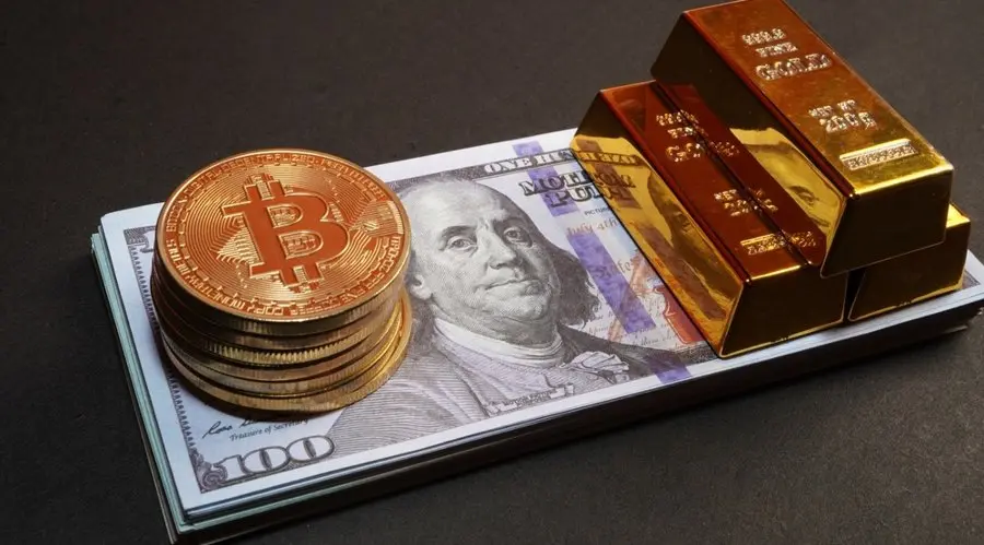 A stack of gold Bitcoin tokens and gold bullion bars resting on a bundle of 100 US dollar bills.