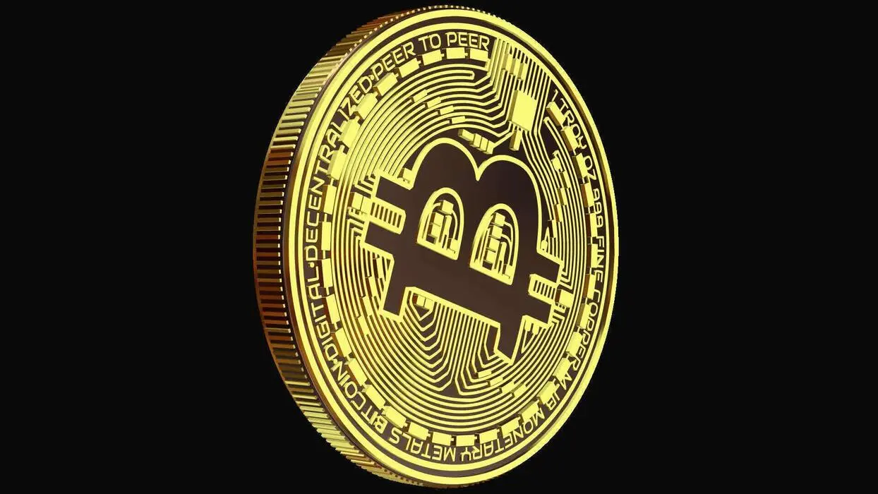 A shiny gold physical Bitcoin coin with the B symbol and circuit board patterns against a black background