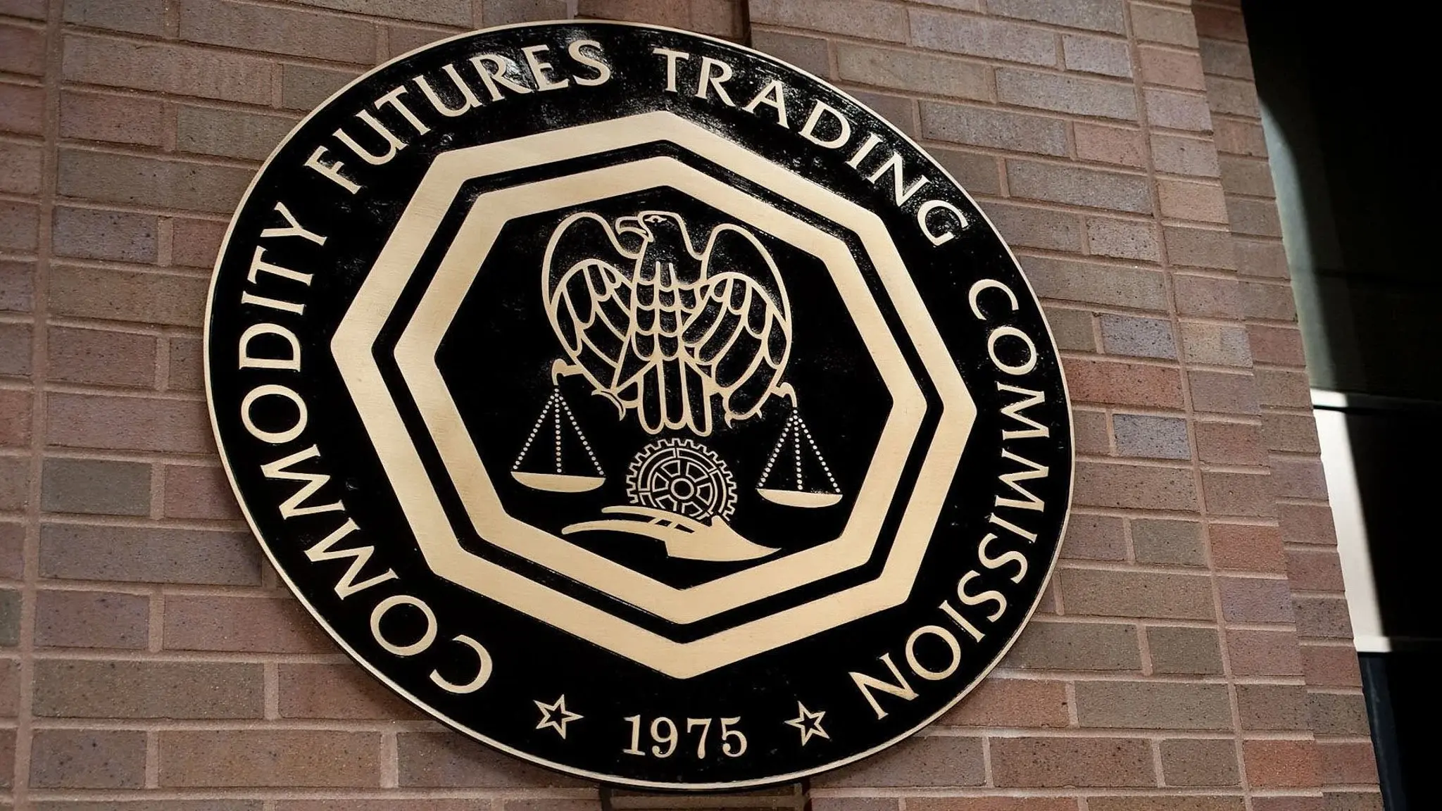 The official bronze seal of the Commodity Futures Trading Commission mounted on a brick wall.
