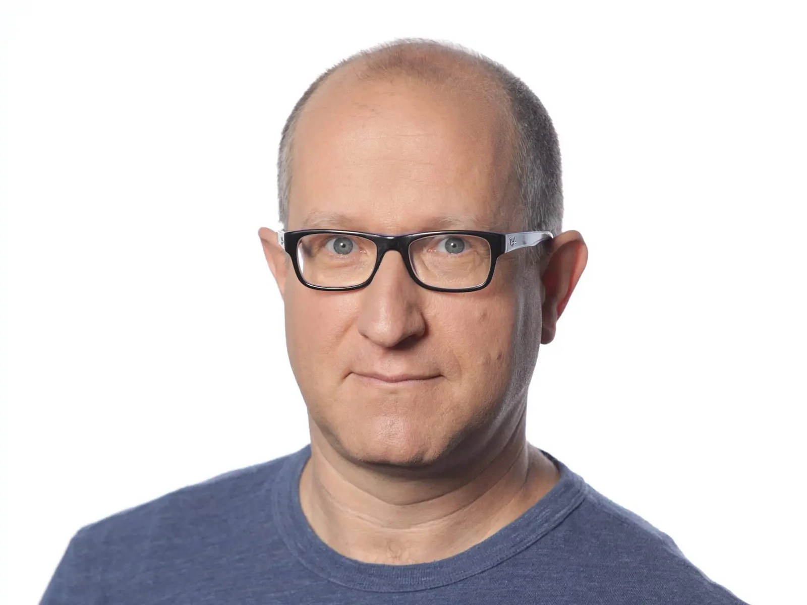 Headshot of Eli Ben-Sasson wearing black rectangular glasses and a blue crew-neck t-shirt against a white background.