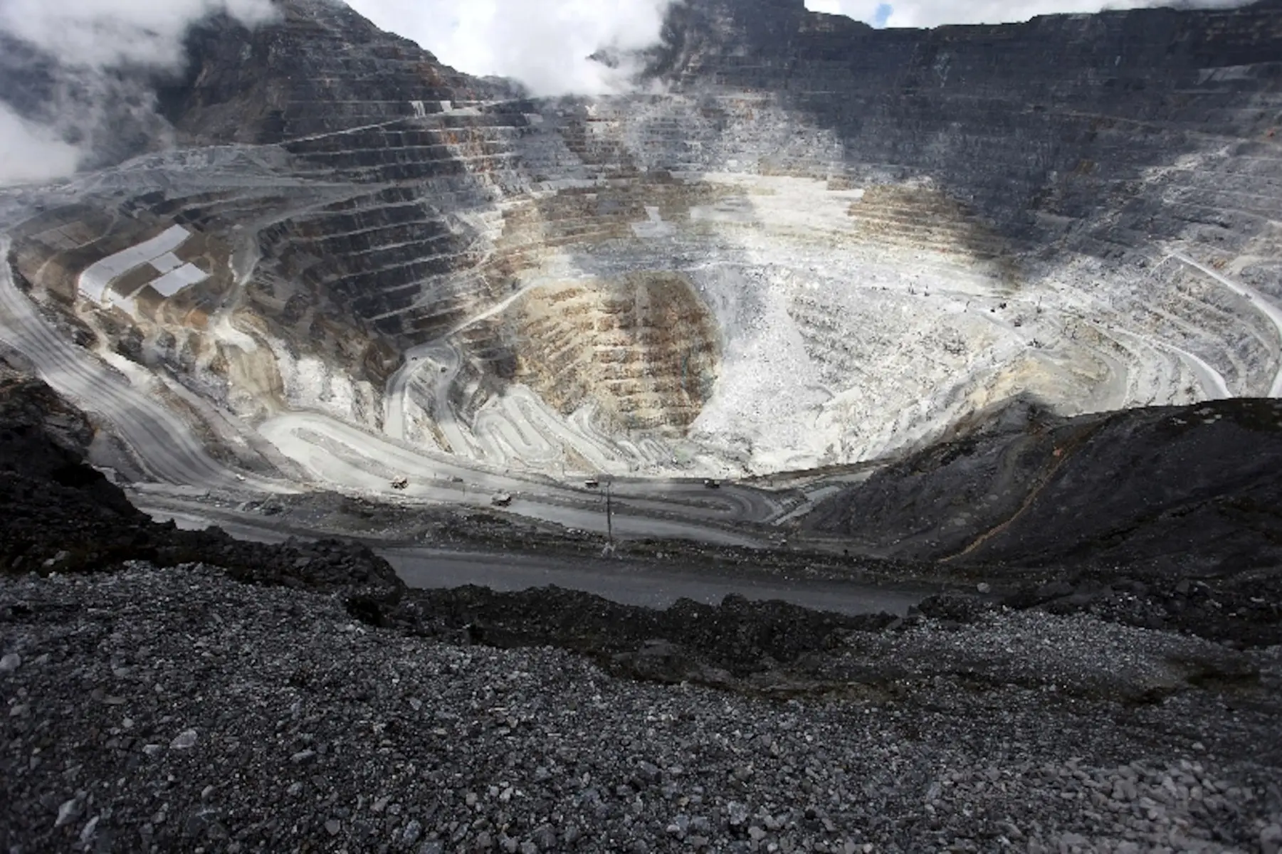 Wide aerial view of the massive open-pit Grasberg mine with terraced rock walls and winding roads