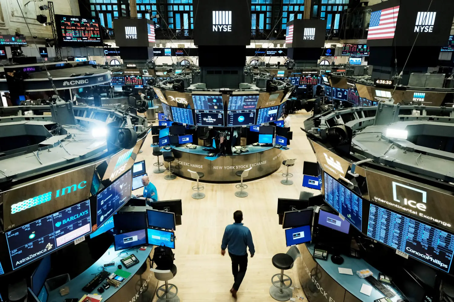Interior view of the New York Stock Exchange trading floor featuring digital displays, trading pods, and a trader.
