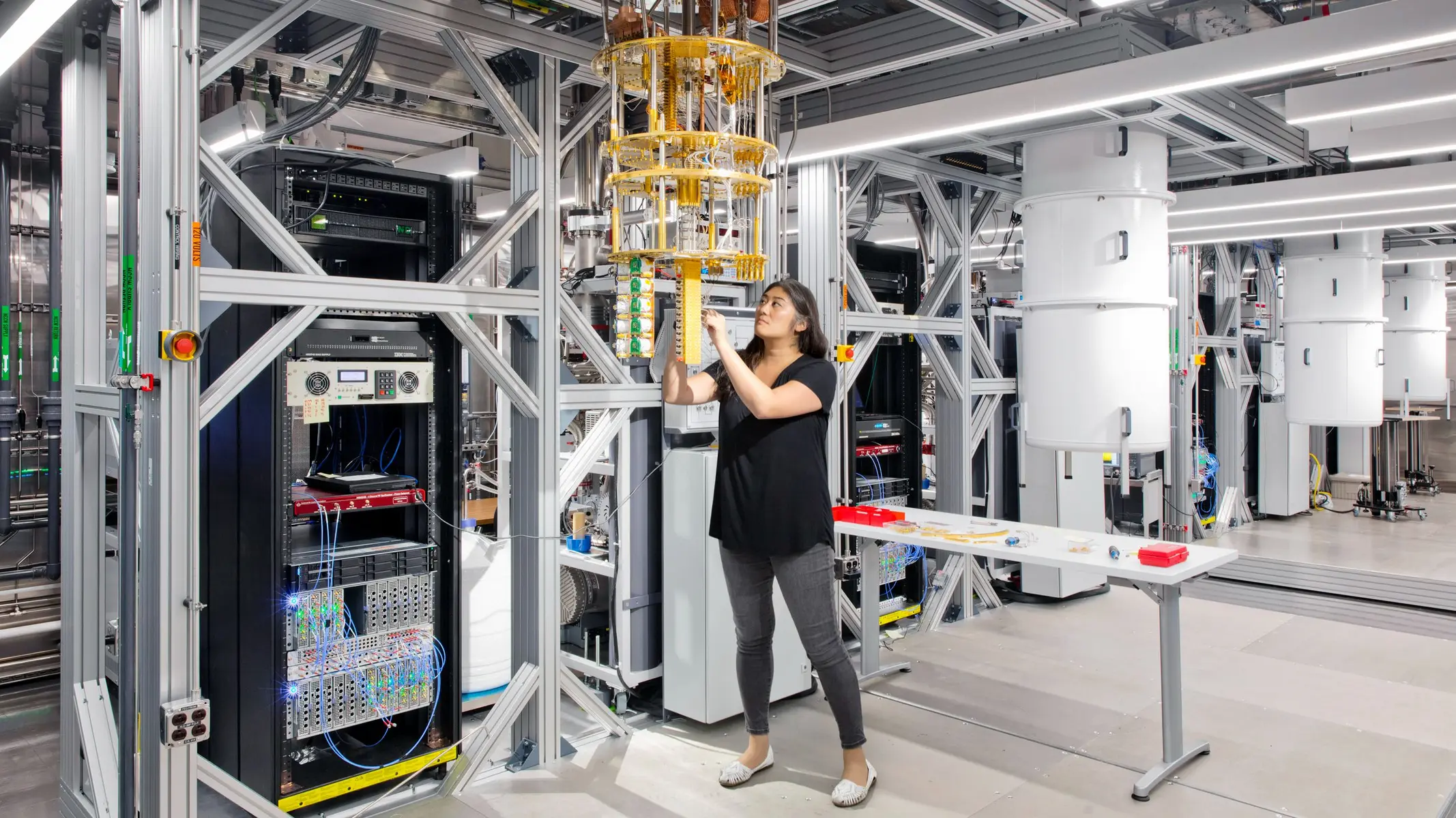 A researcher adjusting a golden dilution refrigerator in a quantum computing laboratory