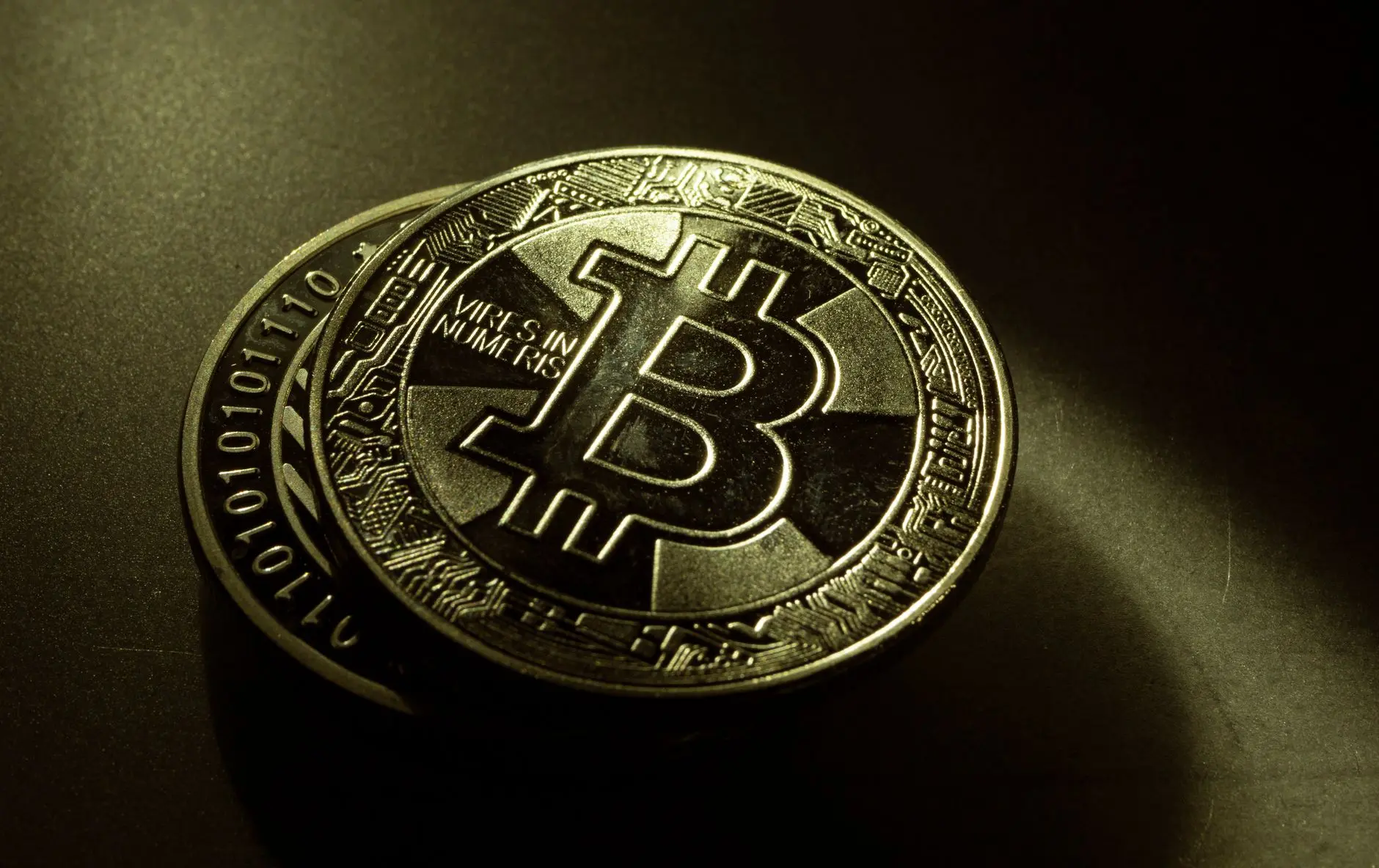 Close-up of two gold-colored physical Bitcoin coins with the Bitcoin symbol and circuitry patterns