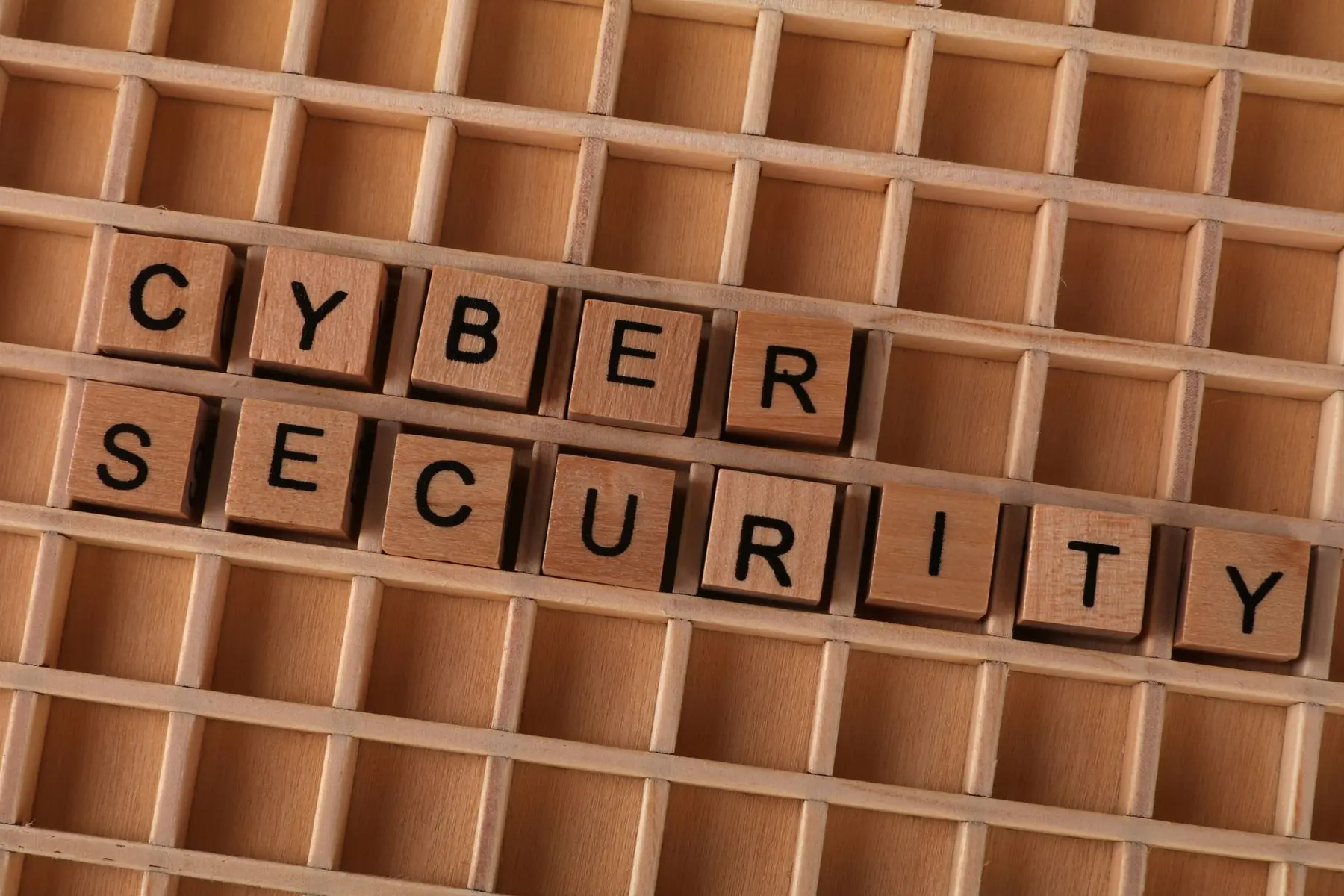 Wooden letter blocks spelling 'CYBER SECURITY' arranged in a grid tray