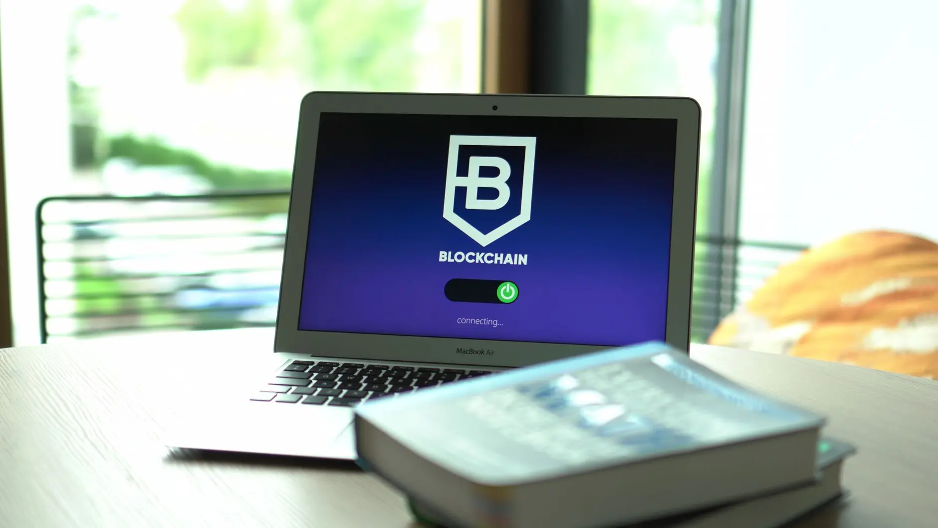 Laptop screen displaying a shield logo with the letter B and the word BLOCKCHAIN