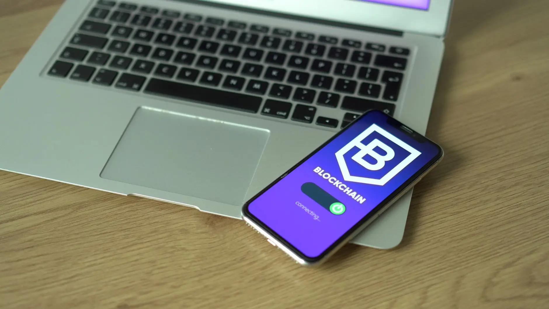 A smartphone displaying the Blockchain wallet app logo resting on a silver laptop keyboard.