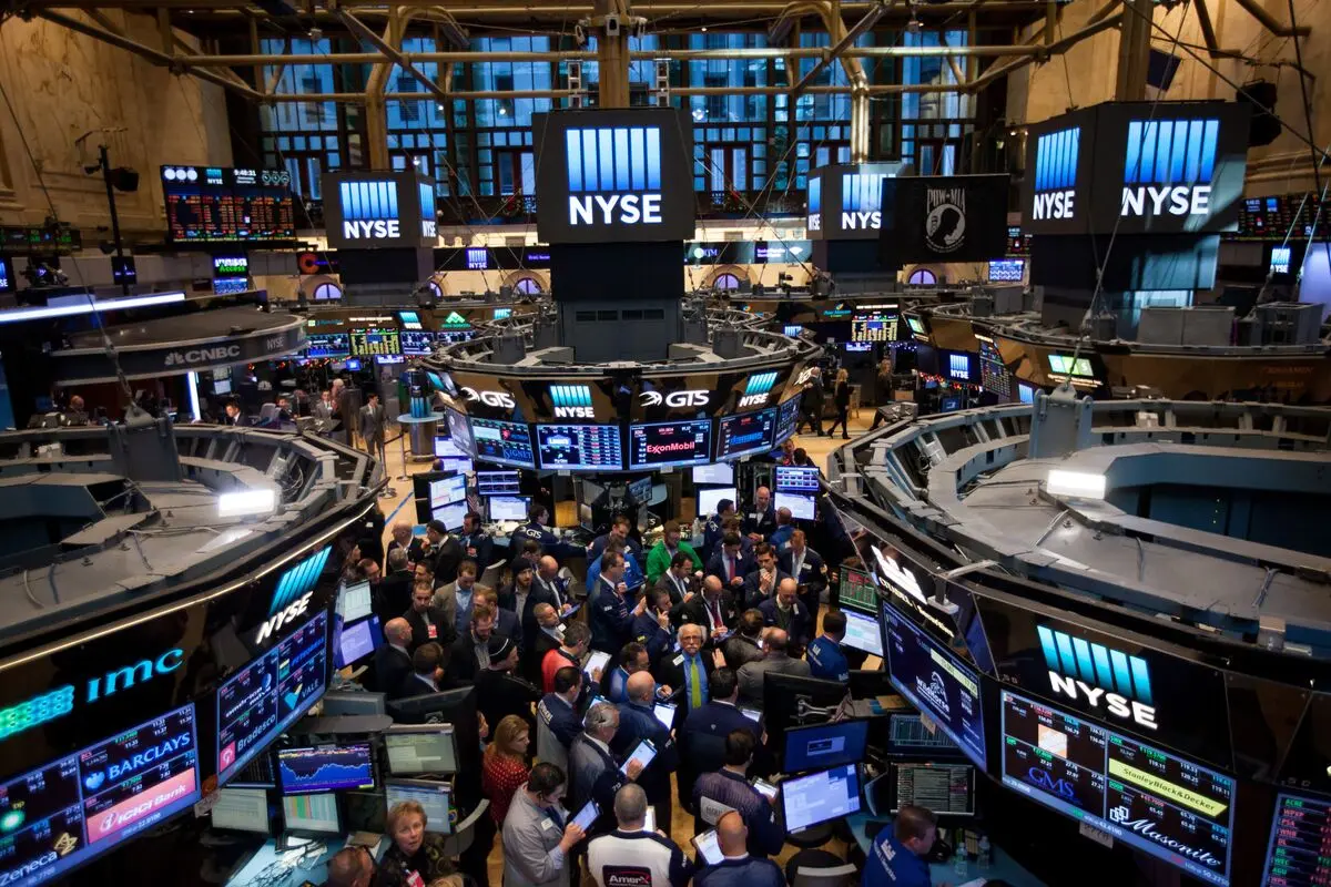 Wide shot of the New York Stock Exchange trading floor with traders and large NYSE digital displays