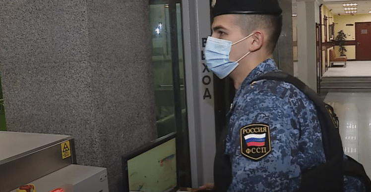 A Russian bailiff enters a building in search of a suspected debtor.