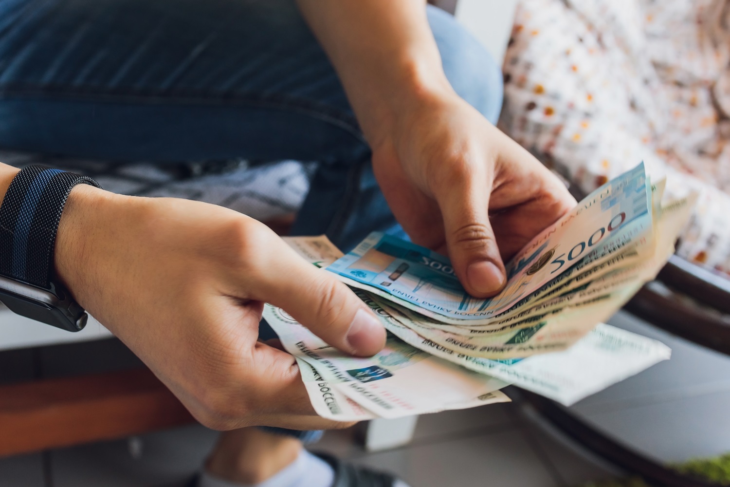 A person’s hand as they count Russian ruble banknotes.