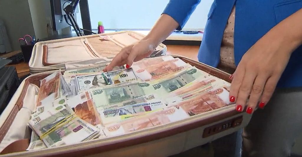 A news reporter demonstrates how much money could fit into the kind of &ldquo;cash-filled suitcases&rdquo; Bitmama&rsquo;s offices allegedly received from customers.