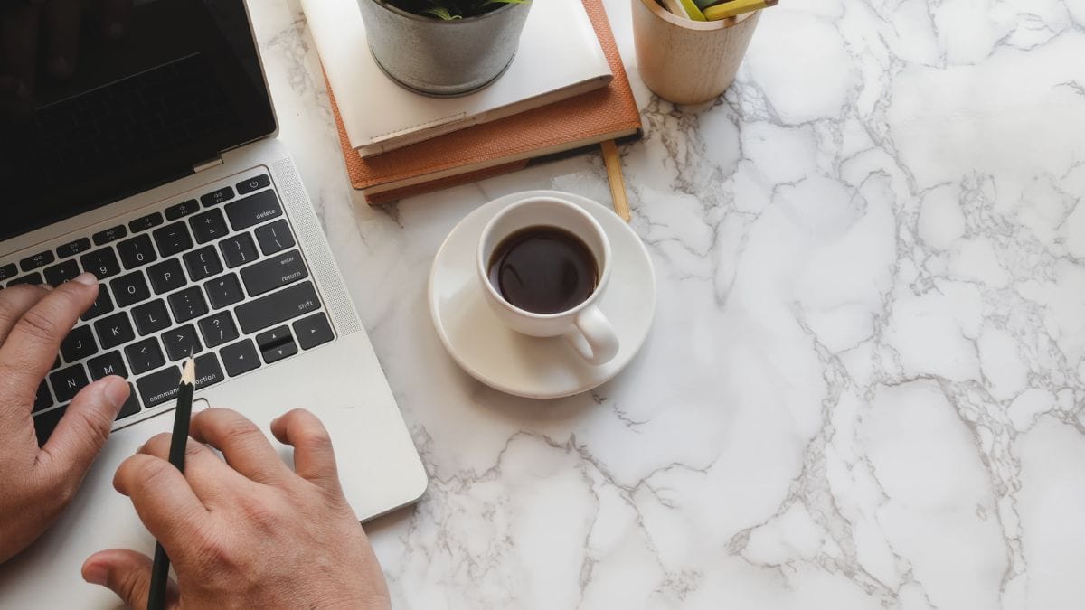 Yritykset pärjäävät entistä paremmin Suomessa. Kuvassa kahvikuppi ja tietokone toimiston pöydällä ylhäältä kuvattuna.