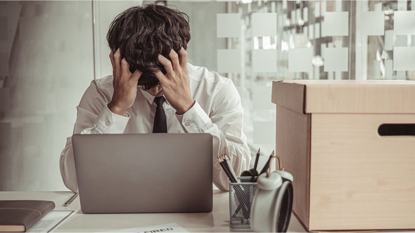 Työttömyysennuste on huonontunut kesäkuussa 2024. Kuvituskuvassa mies pitelee kasojaan työpöydän äärellä.