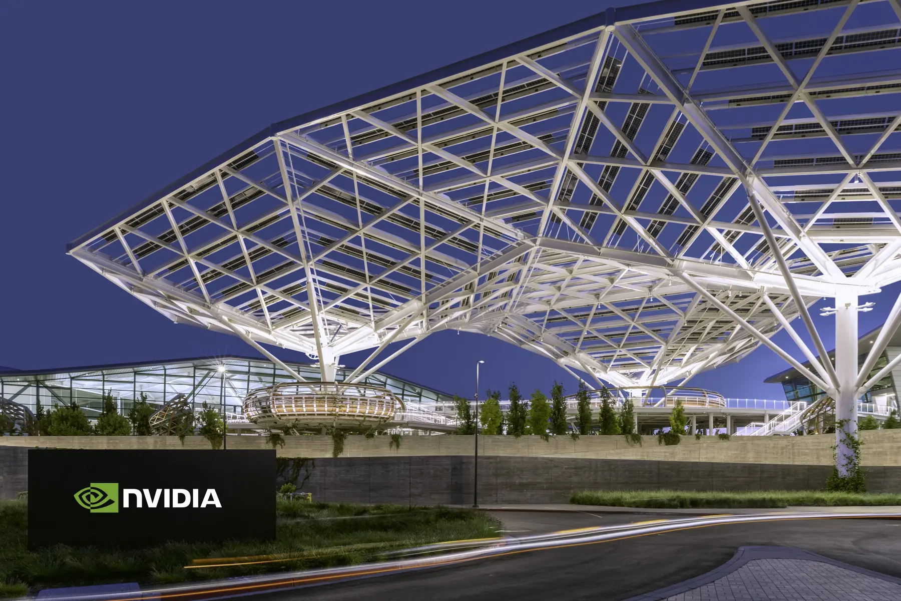 Exterior view of the Nvidia headquarters featuring a geometric white steel canopy and an Nvidia logo sign.