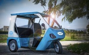 مركبة توك توك عليها شعارeTukTuk وفي الخلفية سماءٌ صافيةٌ وأشجار