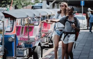 امرأتين تمشيان بجوار عدد من مركبات التوك توك