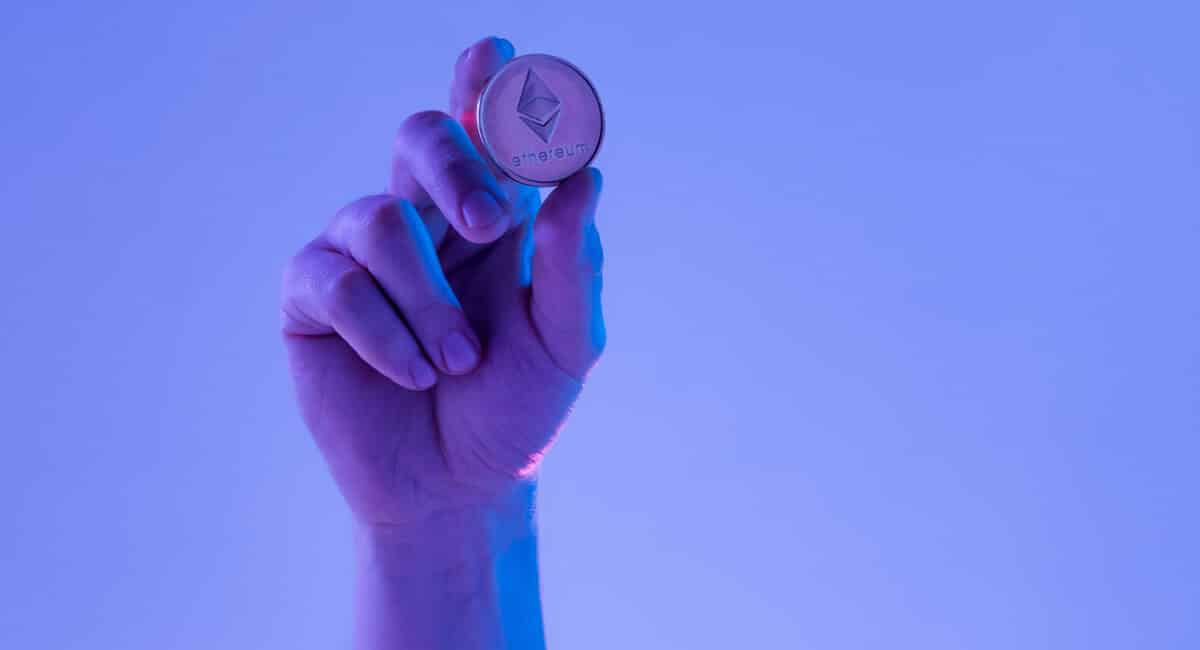 يدٌ تمسك عملةً معدنيةً تحمل شعار إيثيريوم