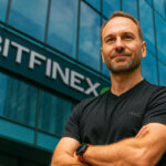 Paolo Ardoino stands confidently with arms crossed in front of the Bitfinex headquarters, wearing a black Tether shirt, reflecting his role in a crypto-focused interview about Bitcoin and Ethereum options markets.
