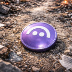 A purple Aave token lying in rubble as explosions burn in the background, reflecting rising turmoil and internal conflict threatening the protocol’s $52B ecosystem.