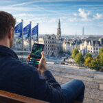 A man reviews crypto market data on his phone overlooking an EU landmark, reflecting new 2026 rules requiring crypto providers to collect tax information from residents.