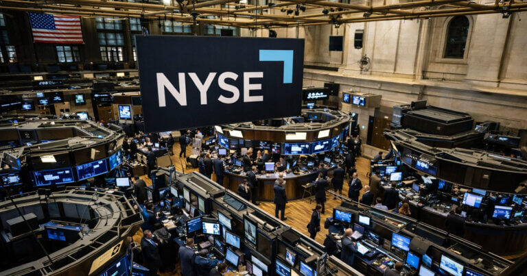 Traders work beneath a NYSE banner on the exchange floor, signaling a new blockchain system using stablecoins to process dividends inside Wall Street plumbing